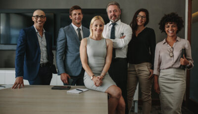 Posed image of C-suite executives of many races, ages, and genders in conference room