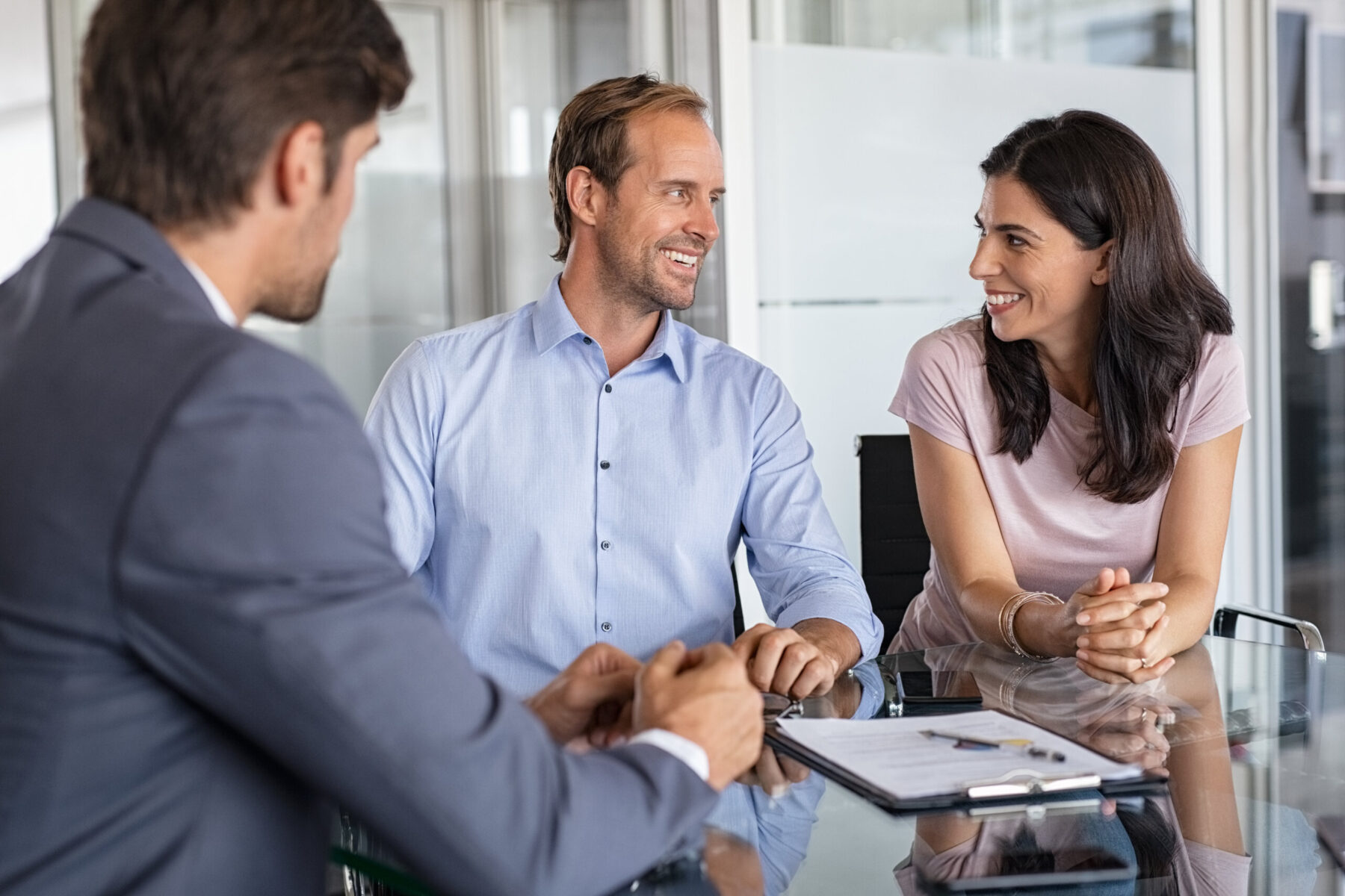 Mature couple discusses financial plans with retirement advisor in modern office